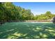 A meticulously maintained private tennis court with green surface and surrounding trees at 1385 Northcliff Trce, Roswell, GA 30076
