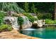 Waterfall feature cascading into swimming pool with lush landscaping at 1385 Northcliff Trce, Roswell, GA 30076