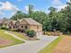 Wide driveway leading to a three-car garage, with manicured landscaping and basketball hoop at 212 Wilshire Ter, White, GA 30184