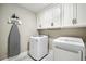 Well-equipped laundry room with white cabinets, modern appliances, and an ironing board at 212 Wilshire Ter, White, GA 30184