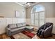 Well-lit living room showcasing hardwood floors, a gray sectional, and a tall arched window at 212 Wilshire Ter, White, GA 30184