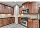 Stylish kitchen boasts rich wood cabinets, black countertops, and stainless-steel appliances at 5207 Merrimont Dr, Alpharetta, GA 30022