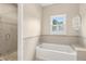 Bright bathroom featuring a tub, shower, tiled walls, and a window at 2260 Burlington Ln, Snellville, GA 30078