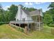 An exterior view of the white home featuring a deck, screened porch, and mature trees at 326 Seldom Seen Trl, Canton, GA 30115