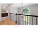 Upper hallway features hardwood floors, black iron railing, light grey walls, and an arched window at 3638 Sope Creek Farm Se, Marietta, GA 30067