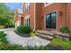 Elegant brick home entrance featuring a stone pathway, a set of black double doors, and lush landscaping at 542 Fairway Dr, Woodstock, GA 30189