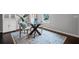 Inviting dining area with a glass table, cushioned chairs, hardwood floors, and a decorative rug at 149 Archie Way, Woodstock, GA 30188