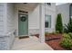 Inviting front door with a green door, white trim, a charming welcome mat, and decorative landscaping at 149 Archie Way, Woodstock, GA 30188