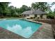 Backyard pool featuring stone trim, an outdoor patio, and mature trees, perfect for relaxation and entertaining at 3261 Stonecreek Ct, Suwanee, GA 30024