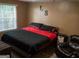 Cozy bedroom with a black and red comforter, a side table and window at 3269 N Winds N Trl, Douglasville, GA 30135