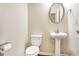 Cozy powder room features a pedestal sink, round mirror, and toilet with classic fixtures at 3179 Woodward Down Trl, Buford, GA 30519