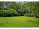 A spacious backyard with lush green lawn, mature trees and red storage shed at 2201 Plantation Ln, Atlanta, GA 30341