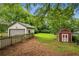 Expansive backyard with green grass, mature trees, garage, and charming red storage shed at 2201 Plantation Ln, Atlanta, GA 30341