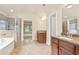 Bathroom featuring dual sinks, a glass enclosed shower, soaking tub, and doorway to the adjacent bedroom at 2720 Tuscany Park Dr, Lawrenceville, GA 30043