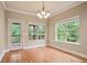 Bright dining room featuring hardwood floors, two windows, elegant chandelier, and a door to a private balcony at 2720 Tuscany Park Dr, Lawrenceville, GA 30043