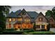 Elegant brick and stone exterior with manicured landscaping, a large front door and a three-car garage at 3155 Wills Mill Rd, Cumming, GA 30041