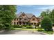 Beautiful daytime exterior of a brick and stone home with lush landscaping and a circular driveway at 3155 Wills Mill Rd, Cumming, GA 30041