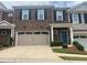 Townhome exterior with brick facade, black shutters, a two-car garage, and manicured landscaping at 209 Ellis Ln, Woodstock, GA 30189