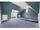An expansive carpeted bonus room with blue walls, featuring stepped platforms and natural light from multiple windows at 7519 Waterview Cv, Douglasville, GA 30135