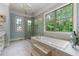 Bright main bathroom featuring a soaking tub, glass shower, chandelier, and large windows at 7519 Waterview Cv, Douglasville, GA 30135