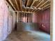 Partially insulated room featuring wooden framing, pink insulation, and a concrete slab ready for flooring at 2753 S Waterworks Rd, Buford, GA 30518