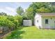 View of a well-maintained backyard with green grass, shed, detached garage, and an orange trumpet vine on a fence at 4150 Glenn St, Powder Springs, GA 30127