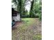 View of an overgrown backyard with tools, an overgrown lawn, and foliage at 2463 Stone Rd, East Point, GA 30344