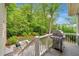 View of the back deck with an outdoor grill, overlooking a lush green backyard with mature trees and landscaping at 3925 Sheldon Ne Dr, Atlanta, GA 30342