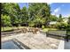 Landscaped backyard featuring a stone patio with built-in firepit and bench seating at 221 Brooke Dr., Alpharetta, GA 30009