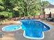 In-ground pool and hot tub surrounded by lush landscaping, and enclosed fence at 4284 Caroline Ct, Douglasville, GA 30135