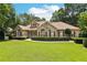 Charming brick home with a lush lawn, beautiful landscaping, and red window shutters under a sunny blue sky at 8110 Lakemont Close, Mcdonough, GA 30253