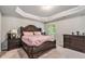 Comfortable main bedroom featuring dark wood furnishings, a tray ceiling, and neutral walls at 10137 Cormac St, Jonesboro, GA 30238