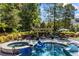 A backyard pool and spa featuring a slide, mature landscaping, and a playhouse at 3111 Old Thompson Mill Rd, Buford, GA 30519
