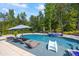 Backyard pool featuring sun loungers and a slide, surrounded by lush greenery and mature trees at 3111 Old Thompson Mill Rd, Buford, GA 30519