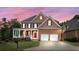 Charming two-story brick home with a covered front porch, two-car garage, and landscaped yard at sunset at 1140 Promontory Drive, Marietta, GA 30062