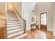 Inviting foyer showcasing hardwood floors, a staircase with decorative iron spindles, and a charming entry door at 13067 Overlook Pass, Roswell, GA 30075