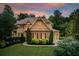 Beautiful two-story home with brick and siding, manicured lawn, and mature trees at sunset at 13067 Overlook Pass, Roswell, GA 30075
