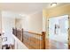 Upstairs hallway with hardwood floors, and iron railing leading to a bedroom with neutral carpet and plenty of natural light at 13067 Overlook Pass, Roswell, GA 30075