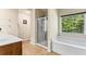 Bright bathroom featuring a separate shower and tub with a large window offering natural light and scenic views at 3547 Edenridge Ct, Buford, GA 30519