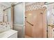 Bathroom shower featuring pink tile, floral wallpaper, grab bar and a sliding glass door at 322 Emily Drive Sw, Lilburn, GA 30047