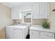 Functional laundry room equipped with a washer, dryer, and storage cabinets at 322 Emily Drive Sw, Lilburn, GA 30047