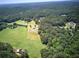 Aerial view of a property surrounded by lush greenery and fields at 668 Spring Place Ne Rd, White, GA 30184