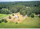 Expansive aerial view of the property featuring a home, outbuildings, and surrounding lush greenery and wooded areas at 668 Spring Place Ne Rd, White, GA 30184