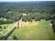 Aerial view of a home surrounded by lush forest and open fields in the distance at 668 Spring Place Ne Rd, White, GA 30184