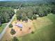 Aerial view of the residence with multiple outbuildings and a sprawling lawn bordered by lush forest at 668 Spring Place Ne Rd, White, GA 30184