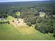Aerial view of a rural property with fields, forest, outbuildings and nearby road at 668 Spring Place Ne Rd, White, GA 30184