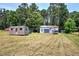 Wide backyard featuring various storage buildings, greenery, and open space at 668 Spring Place Ne Rd, White, GA 30184