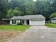 Quaint, single-story home featuring a two-car garage and dark black shutters against a white exterior at 8249 Creekline Ct, Riverdale, GA 30274