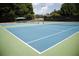 View of a blue and green tennis court with net, surrounded by trees and fencing at 350 Olmstead Way # 29, Alpharetta, GA 30022