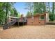 View of a brick home showcasing a back deck and stairs nestled within a lush, wooded backyard at 2695 Peeler Rd, Dunwoody, GA 30360